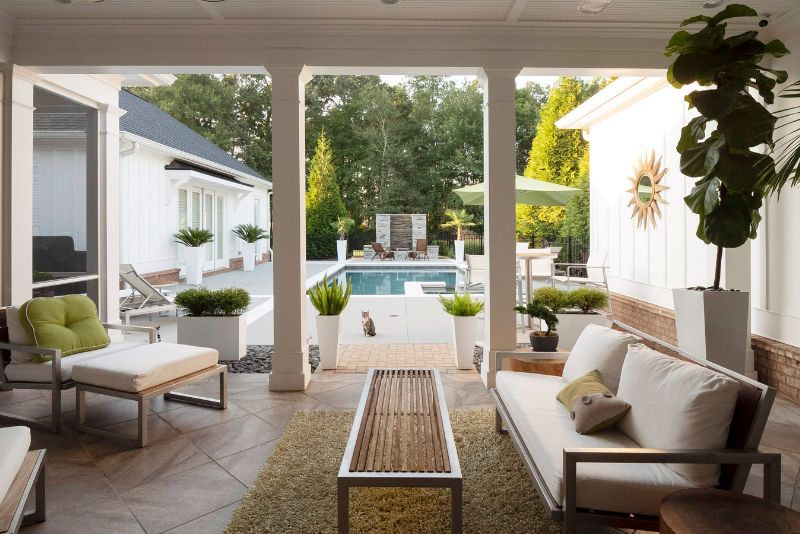 patio next to a pool decorated with lounge seats ad potted plants